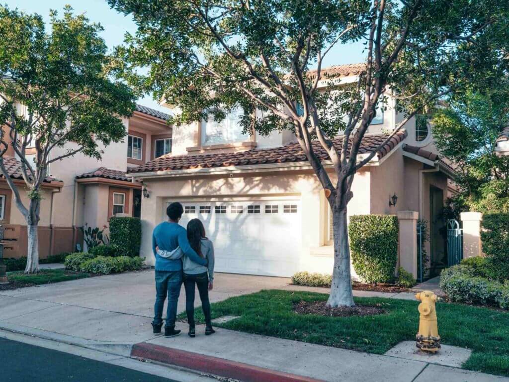 A couple hugging and looking at a house