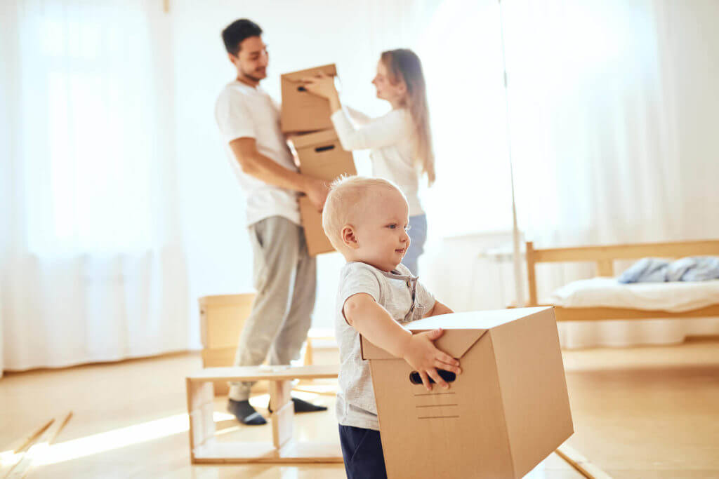 A family relocating, baby carrying a box in front of his parents