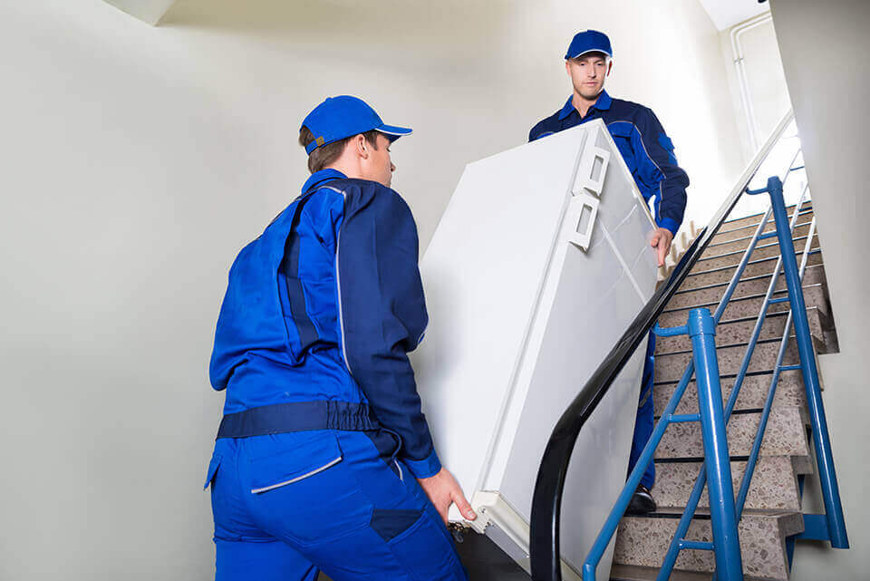 Long-distance movers carrying a refrigerator upstairs