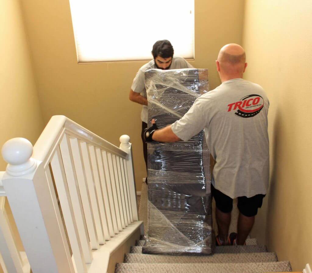 Trico movers taking a piece of furniture down the stairs