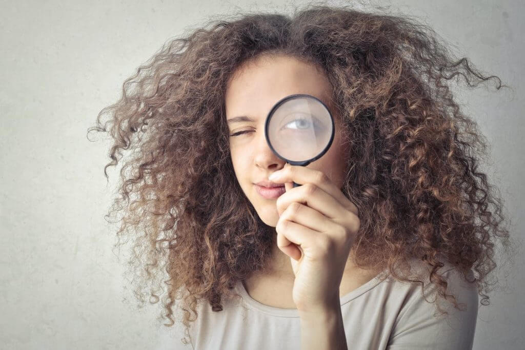 Woman holding a magnifying glass over her eye