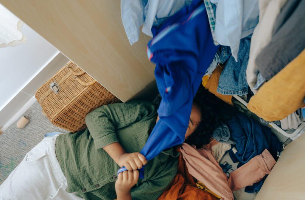 A person lying down covered in clothes before long-distance moving