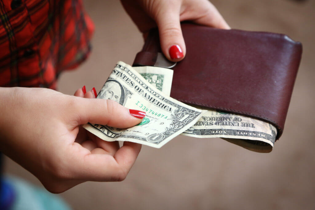 A girl getting cash from her wallet for a tip for long-distance movers