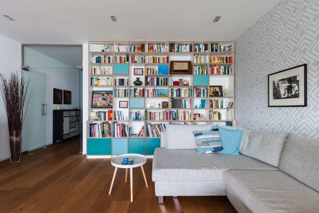 A wall in shelves, a grey sofa and white coffee table in front of it