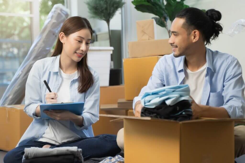 Man putting clothes in a box, a woman next to him checking something on the list