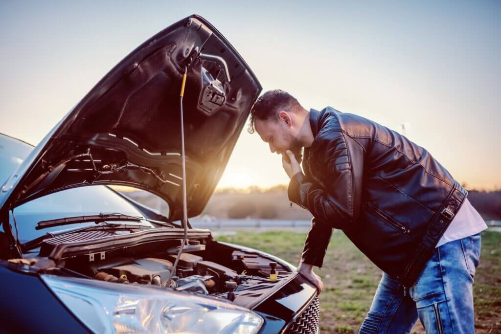 Man looking under the car's hood during long-distance moving