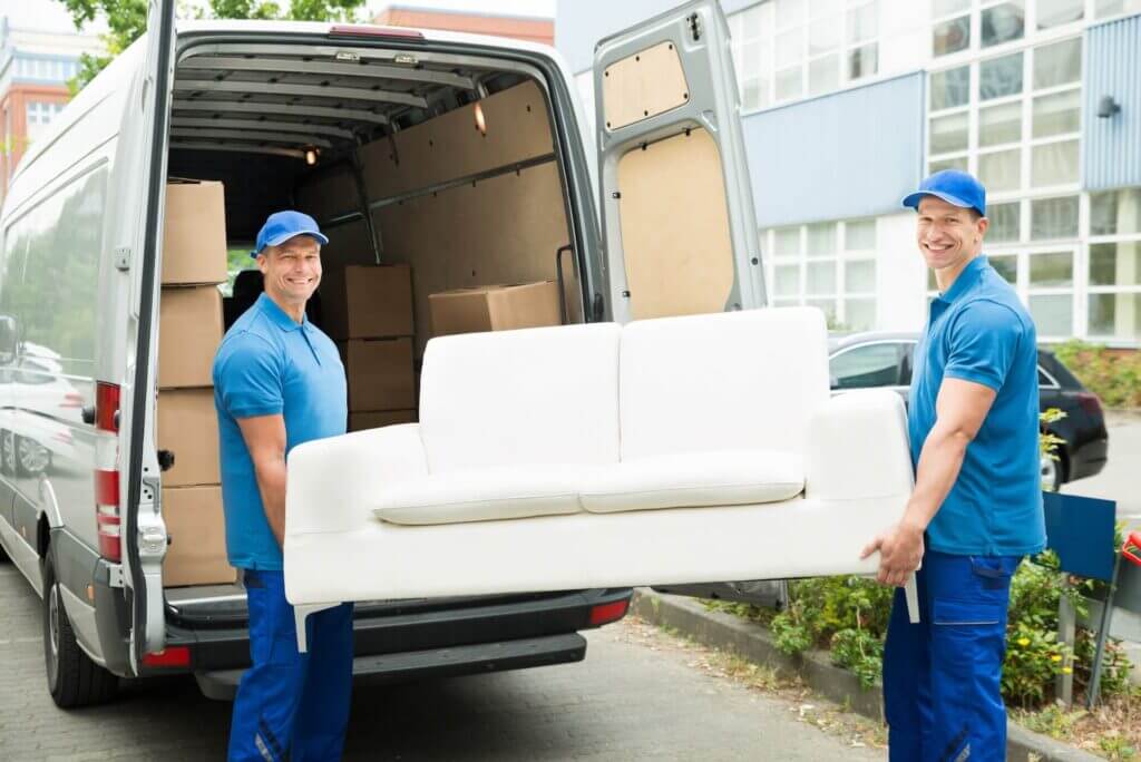 Long-distance movers near me carrying a white couch and smiling