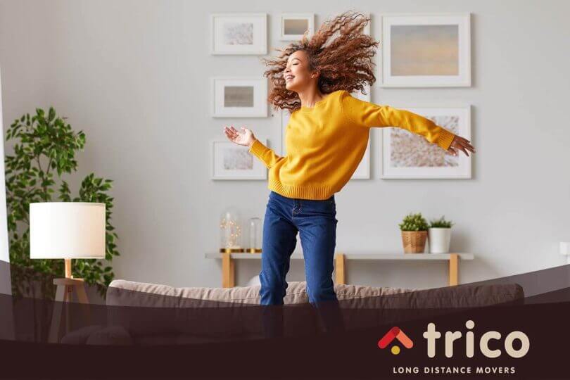 happy girl on the couch Trico Long Distance Movers logo