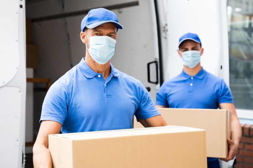 Movers carrying boxes while wearing face masks