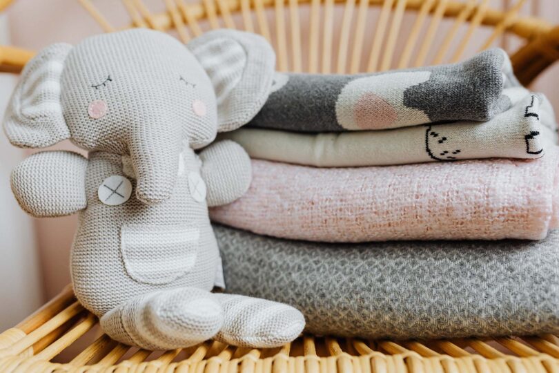 Stuffed elephant toy beside a pile of comforters