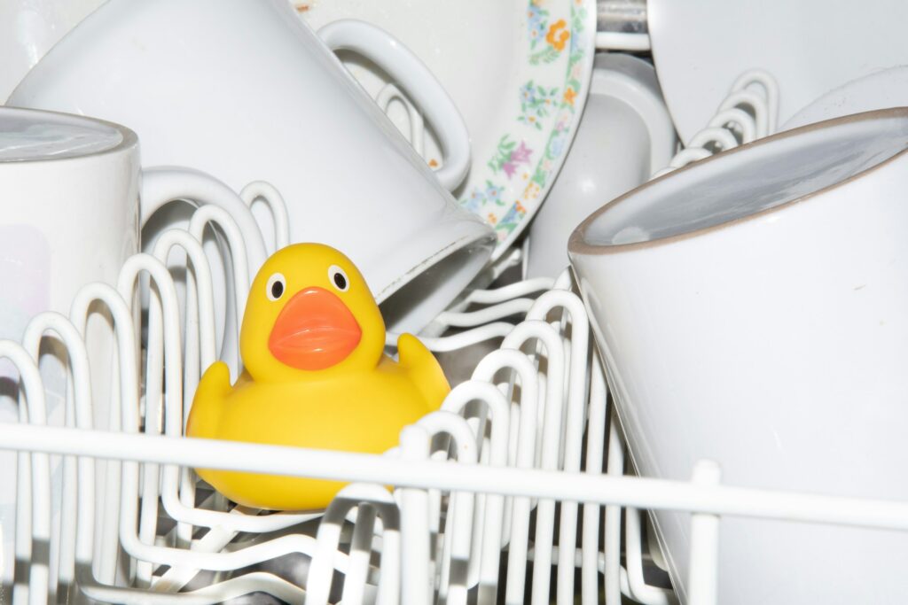 Dishes and a yellow rubber duck in a dishwasher